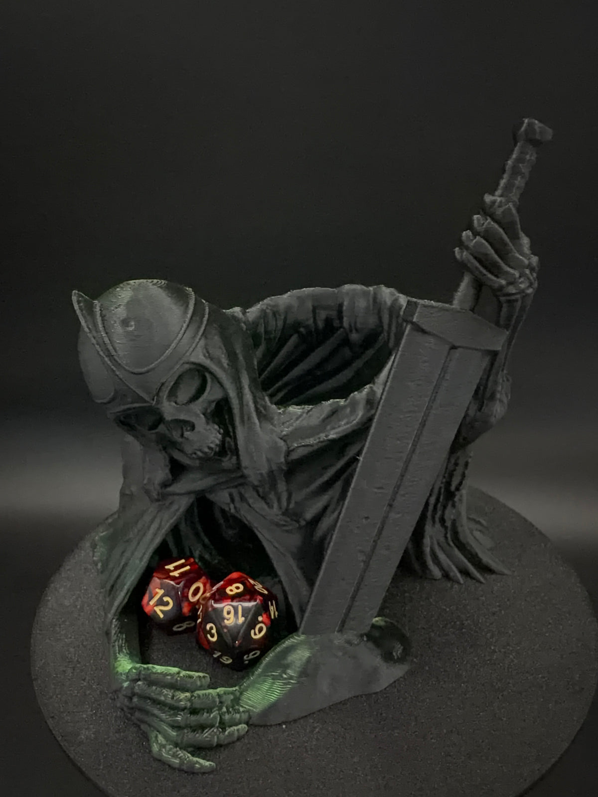 Front view of green and black hooded skeletal dice tower with sword
