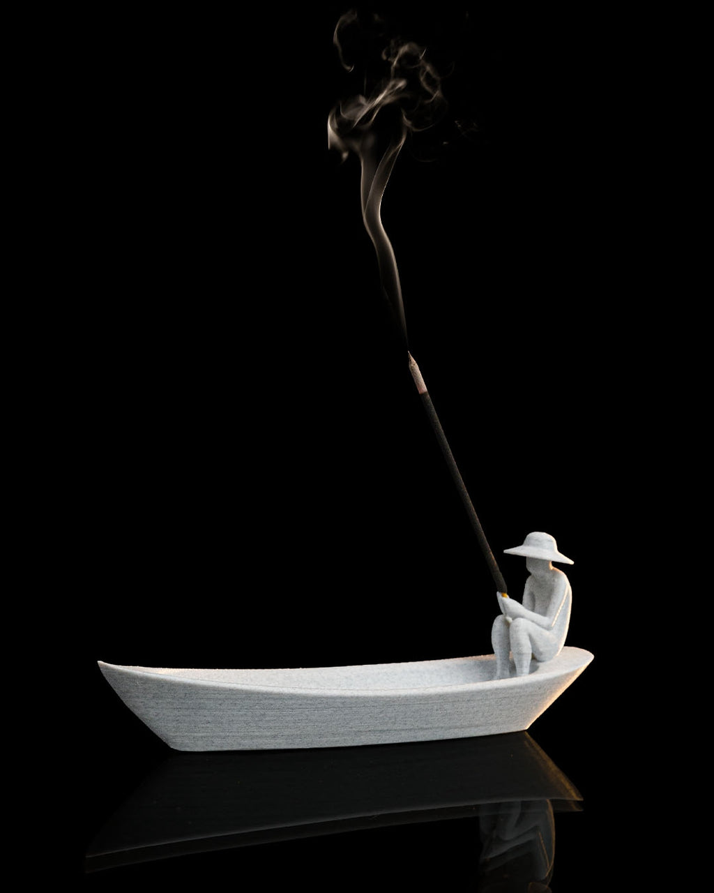 Still Waters incense holder with incense smoke rising from the seated figure in boat-shaped tray